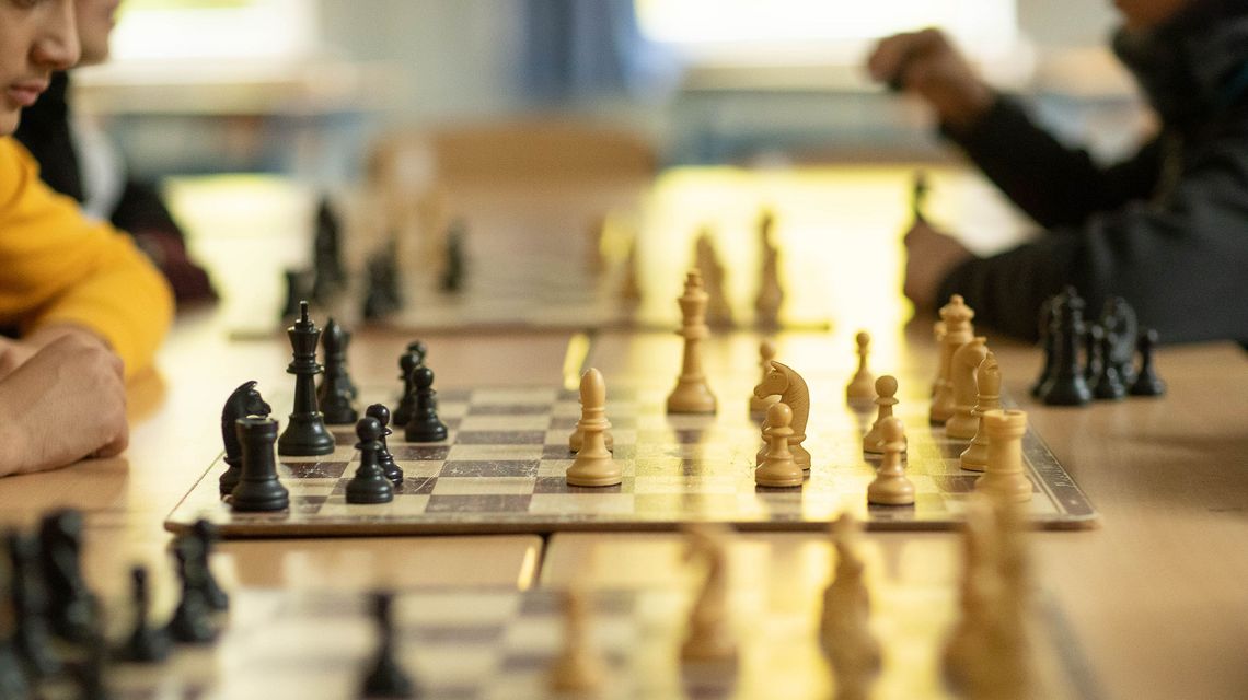 Blick eine Reihe von Schachbrettern, an denen gespielt wird.