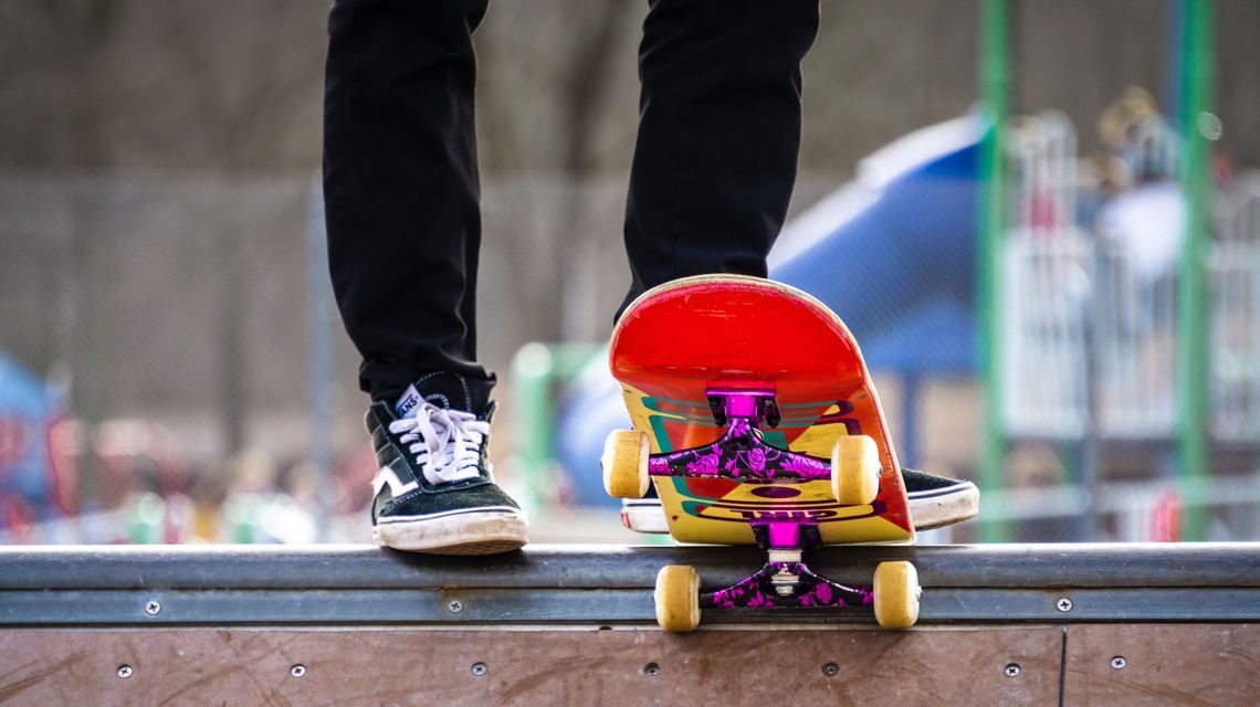 Blick auf die Beine eines jungen Menschen, der Skateboard fahren will.