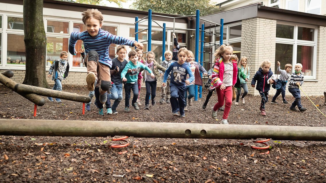 Eine Gruppe von Schulkindern der 1. Klasse toben auf dem Schulhof.