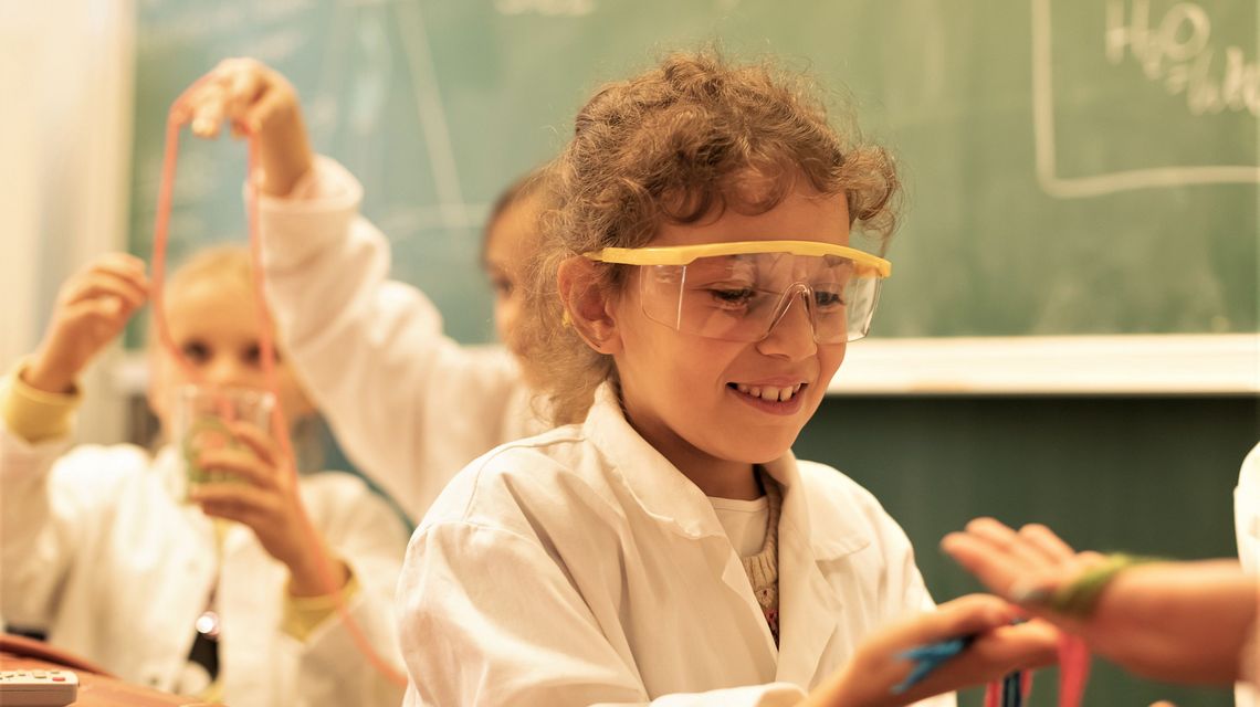 Schüler*innen experimentieren im Chemielabor. Das Mädchen im Vordergrund trägt eine Schutzbrille.