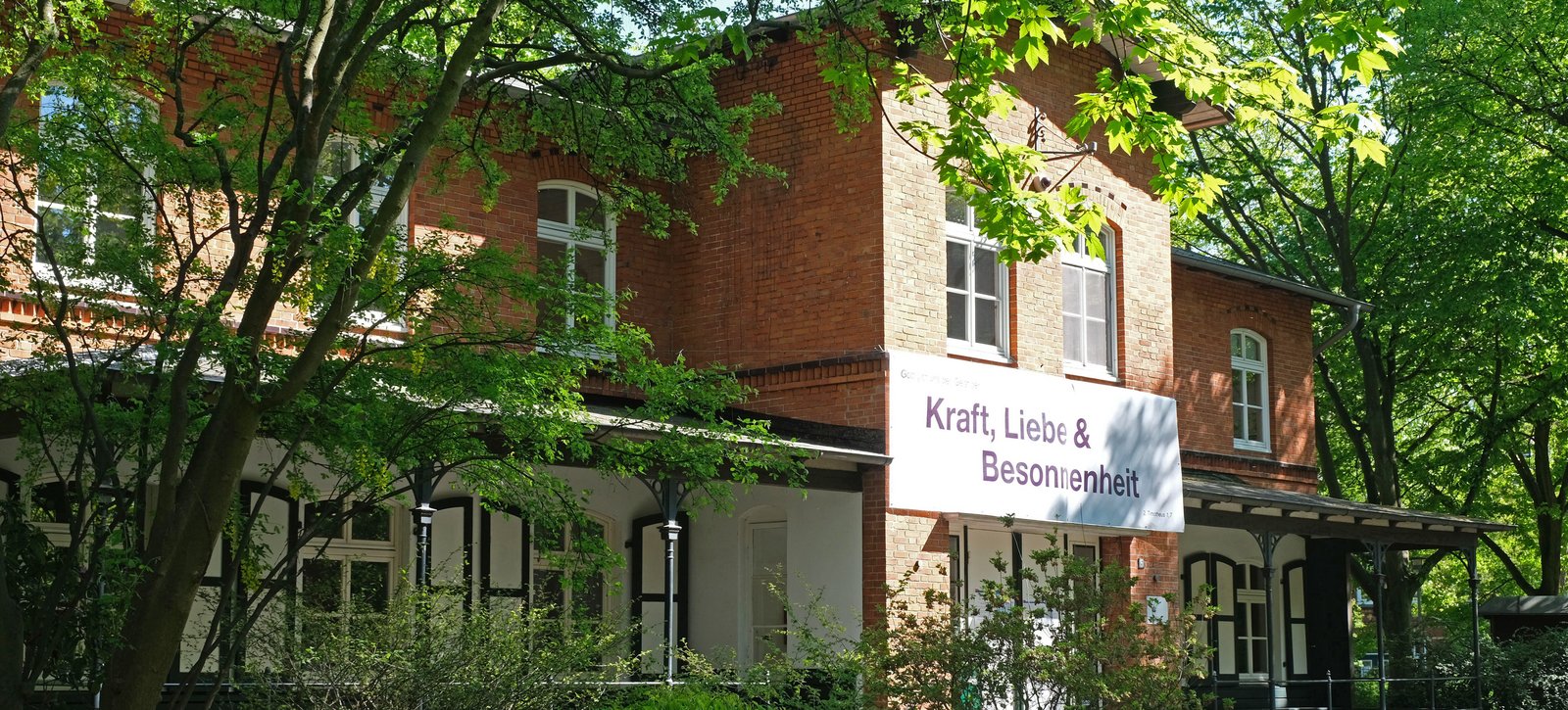 Haus Anker auf dem Stiftungsgelände mit Banner an der Hauswand "Kraft, Liebe & Besonnenheit"