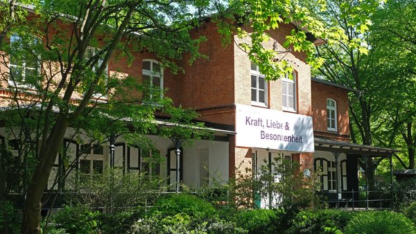 Haus Anker auf dem Stiftungsgelände mit Banner an der Hauswand "Kraft, Liebe & Besonnenheit"