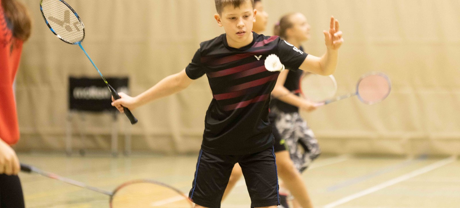 Ein Schüler macht einen Aufschlag beim Badminton in der Halle.